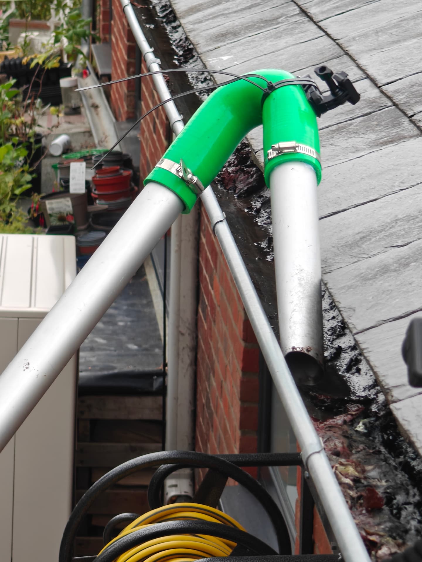Pole-mounted gutter vacuum clearing a gutter from the ground