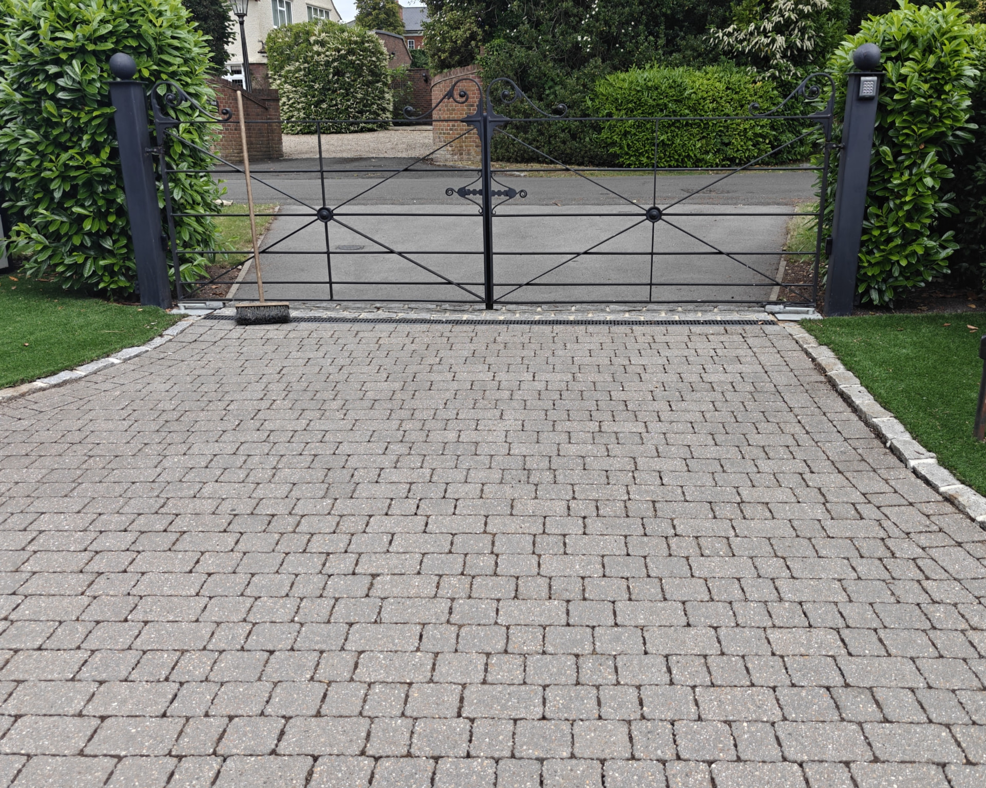 A clean block-paved driveway behind wrought-iron gates